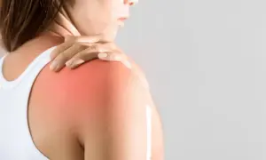 En person håller sin axel där en röd fläck indikerar muskelinflammation i armen.