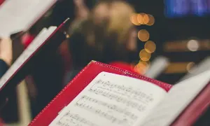 Czerwone księgi z nutami, gotowe do śpiewania kolęd. W tle rozmyte światła.