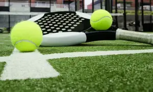 Raqueta de pádel y pelotas sobre césped artificial padel. La cancha está lista para el juego.