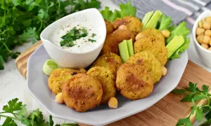 Chrupiące falafelki z ciecierzycy, podane z sosem jogurtowym i warzywami. Idealny falafel przepis na przekąskę.