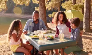 Familia disfrutando un picnic junto a un lago, una escena perfecta de qué hacer en familia al aire libre.