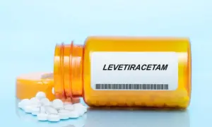 Pomarańczowa butelka z lekiem levetiracetam, z której wysypały się białe tabletki.