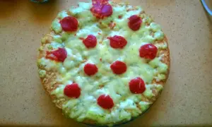 Domowa pizza z serem, zielonym sosem i czerwonymi kółkami pepperoni.