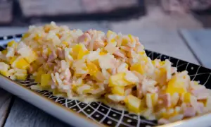 Reissalat mit Mandarinen und Schinken, cremig und fruchtig, auf einem dekorativen Teller serviert.