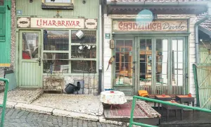 Faszinierende Szene in der Sarajevo Altstadt: Ein Vogel sitzt auf einem Geschäftsschild, davor ein Tisch mit Blumen.