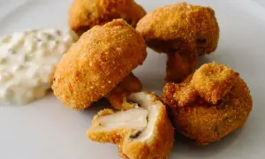 Chrupiące pieczarki w panierce, jedna przekrojona, obok sos tatarski. Idealna przekąska na imprezę.