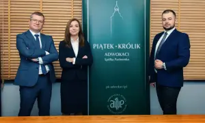 Trzech prawników w garniturach stoi przed zielonym banerem kancelarii "Piątek Królik Adwokaci".