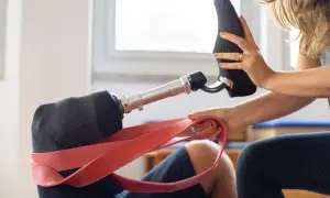Una donna aiuta a indossare una calza su un moncone gamba protesico, con una fascia rossa in primo piano.