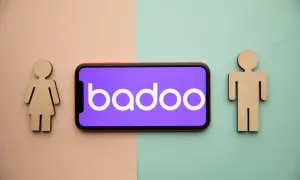 Drewniane figurki kobiety i mężczyzny po bokach telefonu z logo Badoo. Czy to portal randkowy?