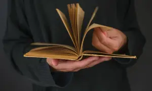 Otwarta, stara książka w dłoniach. Czytanie to podróż, a co to jest nowela? Krótka, wciągająca historia.