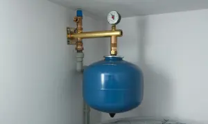 Naczynie przeponowe zamontowane na ścianie, z manometrem i zaworem. Idealne miejsce do instalacji w systemach grzewczych.