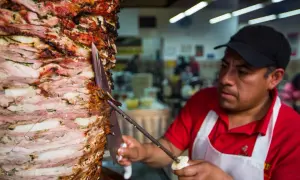 Kucharz kroi obracający się pionowo kebab z warstw mięsa i cebuli.