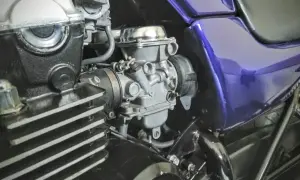 Fragment motocykla z widocznym gaźnikiem i elementami silnika.