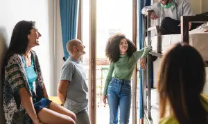 Grupa młodych ludzi rozmawia w pokoju z łóżkami piętrowymi. To idealny przykład, jak działa couchsurfing co to – wspólne podróże i poznawanie nowych ludzi.