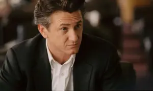 Sean Penn w czarnym garniturze i białej koszuli, wygląda jakby zastanawiał się nad kolejną rolą w swoich filmach.