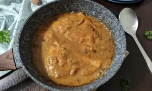 Bitki z indyka w sosie własnym, gotowe do podania. Aromatyczne danie w patelni, ozdobione natką pietruszki.