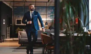 Ein Mann im eleganten dunkelblauen Lounge Suit steht lässig in einem stilvollen Loft.
