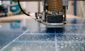 Precyzyjne cięcie plexi szlifierką CNC. Wióry unoszą się w powietrzu podczas pracy maszyny.