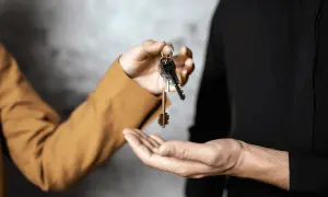 Mani che si scambiano chiavi, simbolo di un immobile in comproprietà abitato da un solo proprietario.