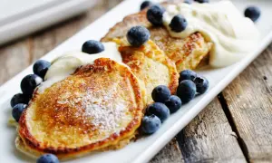 Gyllene pannkakor med havregryn, toppade med vispad grädde och färska blåbär. En härlig frukost eller fika.