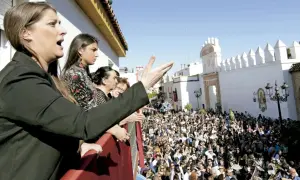 Mujeres en un balcón observan una multitud y escuchan saetas populares.