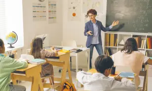 Nauczycielka tłumaczy zadanie, dzieci słuchają. Ile godzin tygodniowo pracuje nauczyciel przedszkola? To pytanie pozostaje bez odpowiedzi, ale lekcja trwa.