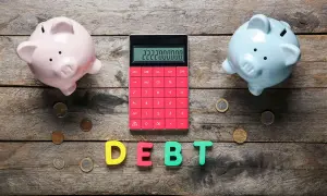 Due salvadanai rosa e azzurro, una calcolatrice rossa con un numero elevato e lettere che formano la parola "DEBT" suggeriscono un **debito residuo** da gestire.