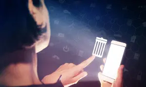 Palec wskazujący dotyka ikony kosza na śmieci, sugerując, jak wyczyścić telefon z niepotrzebnych aplikacji.