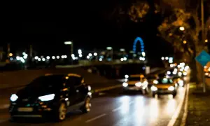 Rozmyte światło uliczne i reflektory samochodów tworzą efekt przypominający astygmatyzm. Nocna droga z migoczącymi światłami.
