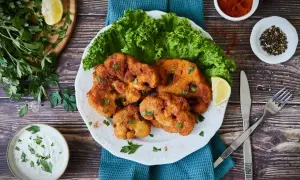 Knuspriges Blumenkohl Schnitzel mit frischem Salat, Zitrone und Dip. Ein Genuss für Vegetarier!