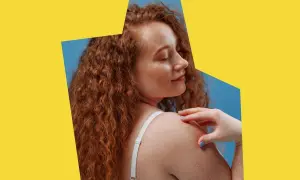 Ruda kobieta z piegami dotyka ramienia. Czy biotyna co to? Witamina B7 wspiera zdrowie skóry i włosów.