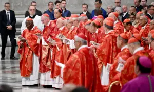 Kardynałowie w czerwonych szatach, przygotowujący się do wyboru papieża, trzymają w rękach dokumenty.
