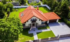 Piękny dom z czerwonym dachem i ogrodem. Zastanawiasz się, ile kosztuje projekt domu?