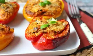 Poivrons farcis colorés, dorés et appétissants, garnis d'une chapelure croustillante et d'une feuille de basilic frais.