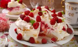 Pyszny tort bezowy z mascarpone i bitą śmietaną, ozdobiony malinami. Idealny na deser!