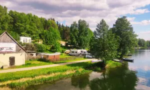 Malowniczy widok na jezioro i lasy, gdzie leżą Bory Tucholskie. Kemping z kamperami i łodziami przy brzegu.