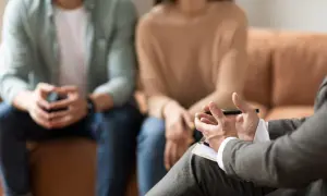 Para rozmawia z terapeutą, który notuje. Sesja skupia się na poprawie ich zdolności poznawczych i komunikacji.