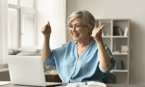 Szczęśliwa kobieta z kciukami w górze, cieszy się z pomyślnej odprawy emerytalnej online.