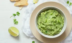 Pyszna pasta z awokado i jajka, podana z nachos i limonką. Idealna na przekąskę.