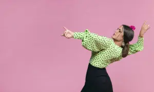 Mujer con blusa verde de lunares y falda negra, lista para bailar sevillanas con gracia y pasión.