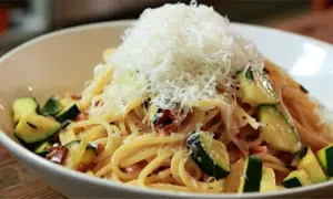 Spaghetti mit Zucchini und Speck, gekrönt mit frisch geriebenem Parmesan. Eine köstliche Zucchini Carbonara.