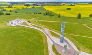 Pomnik Grunwaldzki i amfiteatr na tle pól rzepaku. Trasa turystyczna prowadzi przez zielone wzgórza.