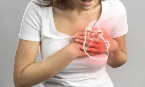 Kobieta trzyma się za serce, na którym widoczny jest zarys i czerwone podświetlenie. Może to symbolizować ból lub podwyższony poziom troponiny.
