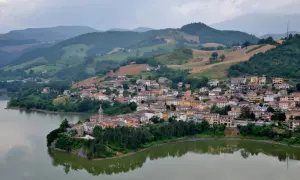 Borgo pittoresco affacciato su un lago, con case colorate e colline verdi sullo sfondo. Un gioiello nascosto nella regione di Urbino.