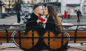 Para spędza romantyczny czas na ławce w kształcie serca, trzymając czerwone serduszka. To świetny pomysł, co można robić z chłopakiem poza domem.