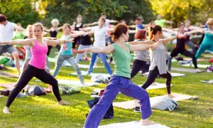 Un groupe de personnes pratique le yoga en plein air, profitant du soleil. Faire du yoga tous les jours apporte calme et équilibre.