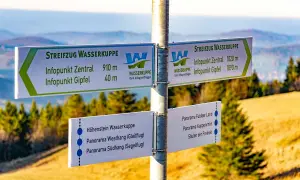 Wegweiser am Gipfel der Wasserkuppe für Wanderer. Hier beginnt der Streifzug Wasserkuppe, mit Zielen wie Infopunkt Zentral und Gipfel.