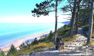 Frau mit Hund auf einem sandigen Pfad mit Blick auf die polnische Ostsee.