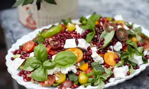 En färgglad sallad med granatäpple, tomater, fetaost och basilika, perfekt som sallad till grillat.