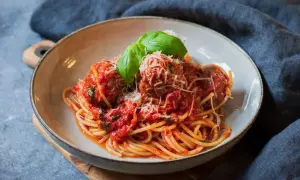 En skål med spaghetti och köttbullar i tomatsås, toppad med parmesan och basilika. En klassisk pasta polpette-rätt.